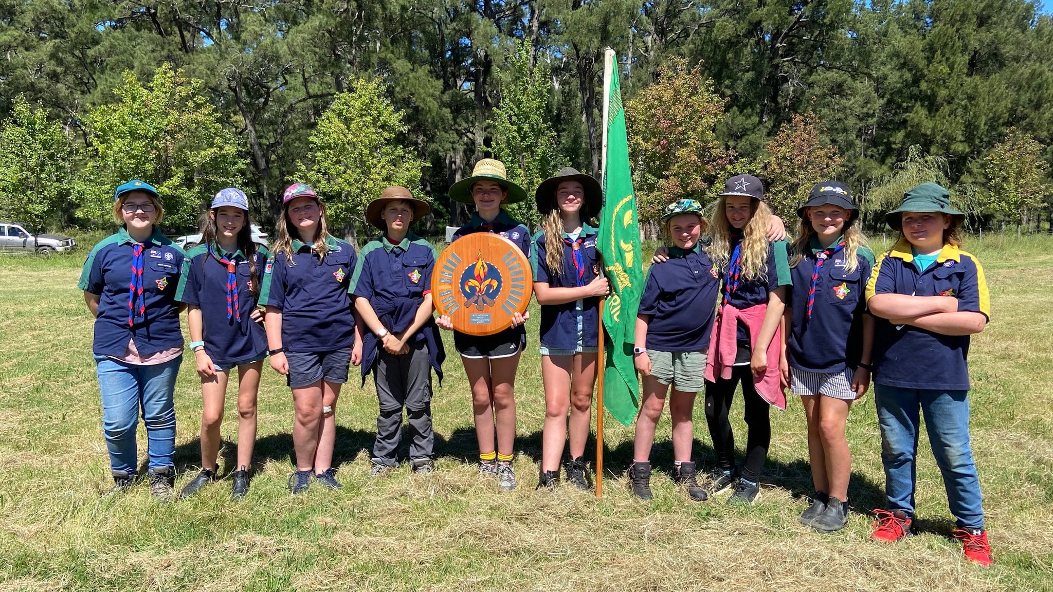 Ten Scouts displaying a trophy shield and a flag